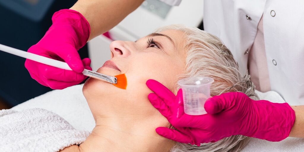 Woman reclined as a chemical peel solution is applied to her face