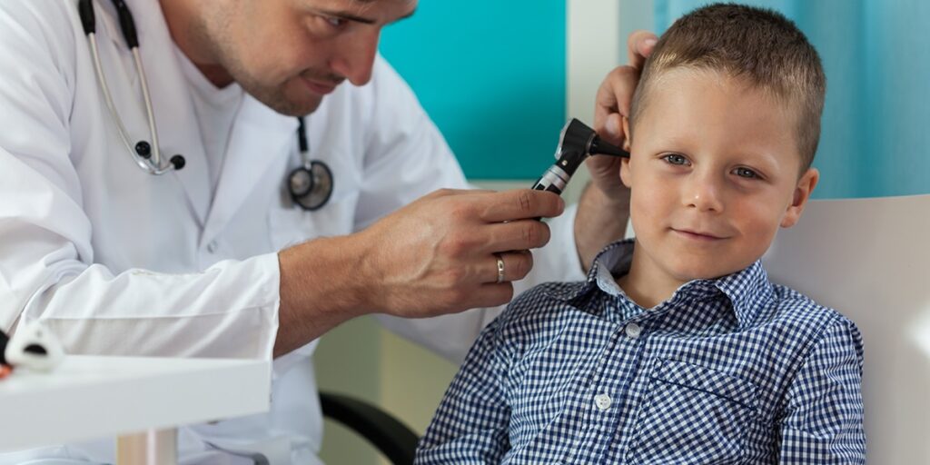 Doctor looking through a otoscope into a boy's ear